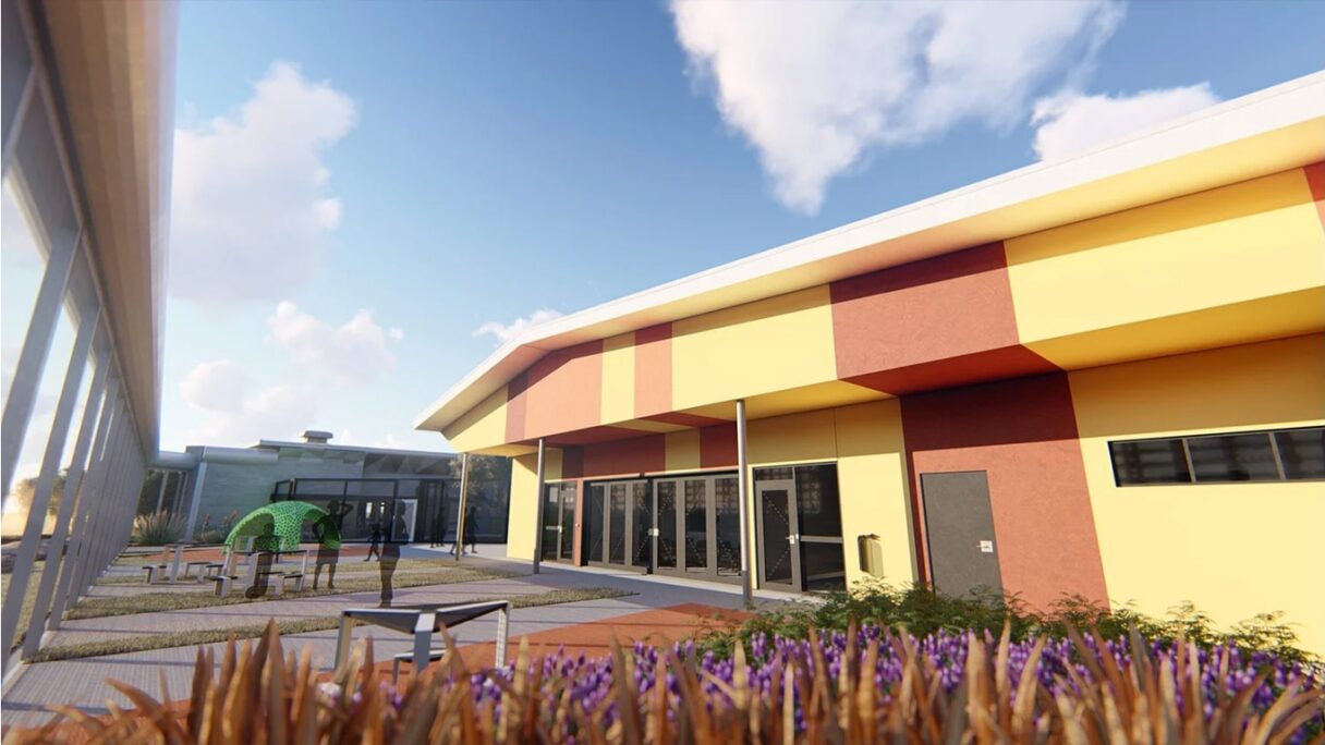Outdoor courtyard with modern building featuring yellow and red striped façade and glass doors.