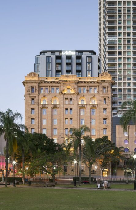 Heritage building with five modern storeys added above, framed by city skyline.