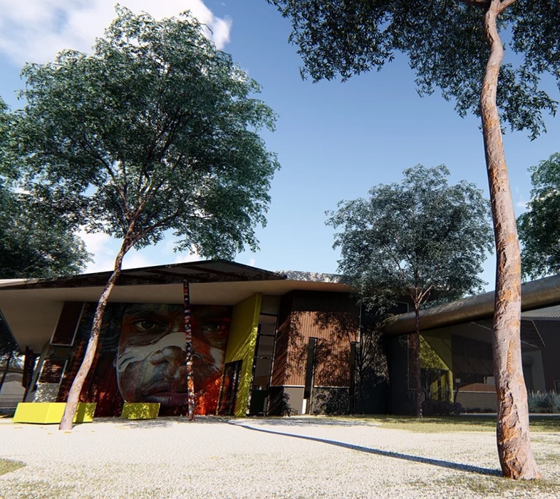 Architectural view of a modern building surrounded by tall trees and an open gravel courtyard.