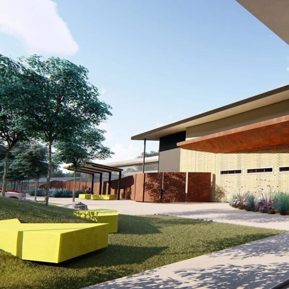 Building entrance with large glass doors, rust-colored canopy, and stone landscaping.